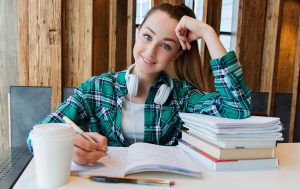 girl at table doing homework looking at camera